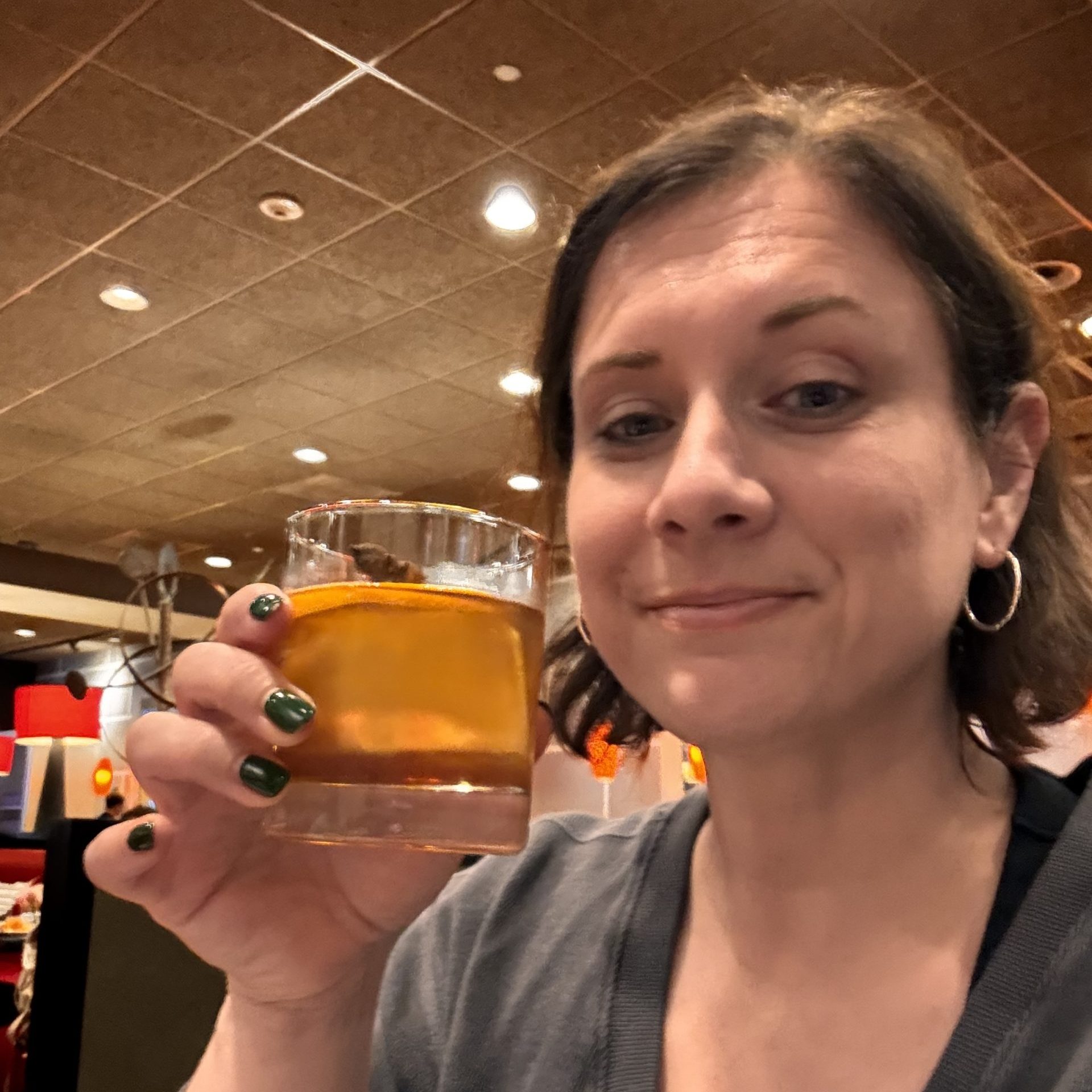 Photo of blog author Mikell Taylor, smiling faintly and holding up a cocktail